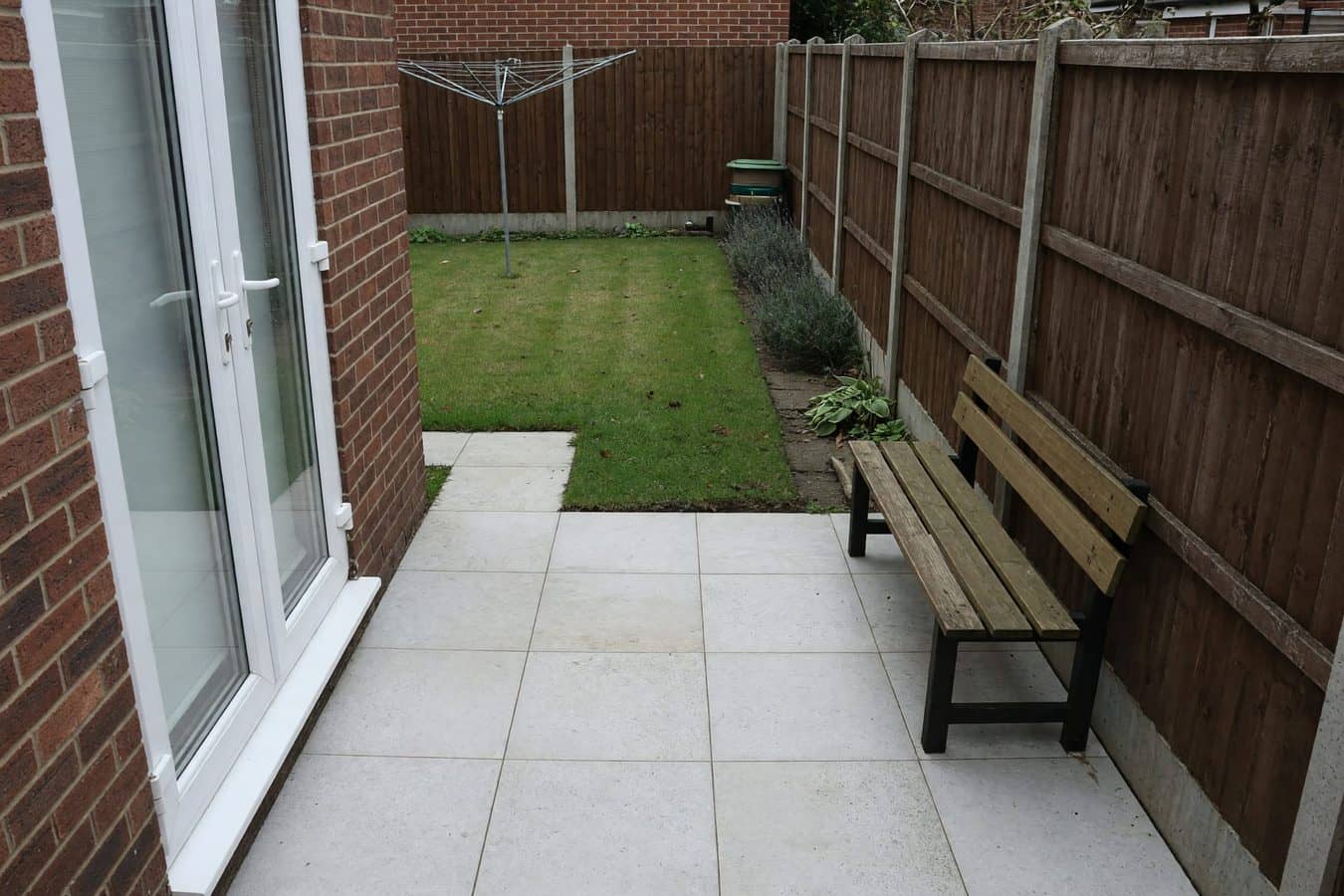 Shaded porcelain pad by the back doors of a Lancashire house, used as a reading nook rather than a dining patio