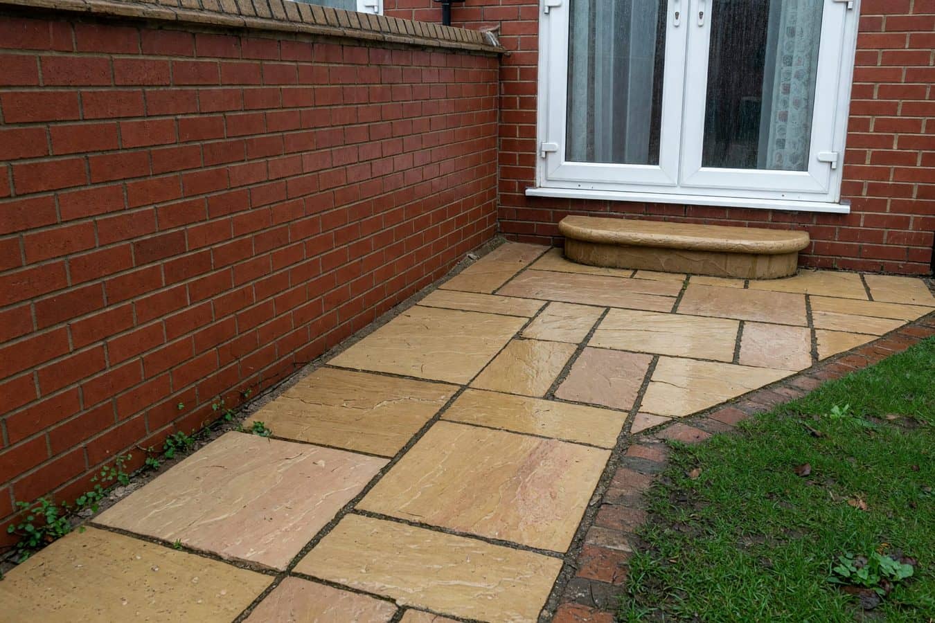 Buff sandstone patio stepped down from white patio doors on a red-brick semi