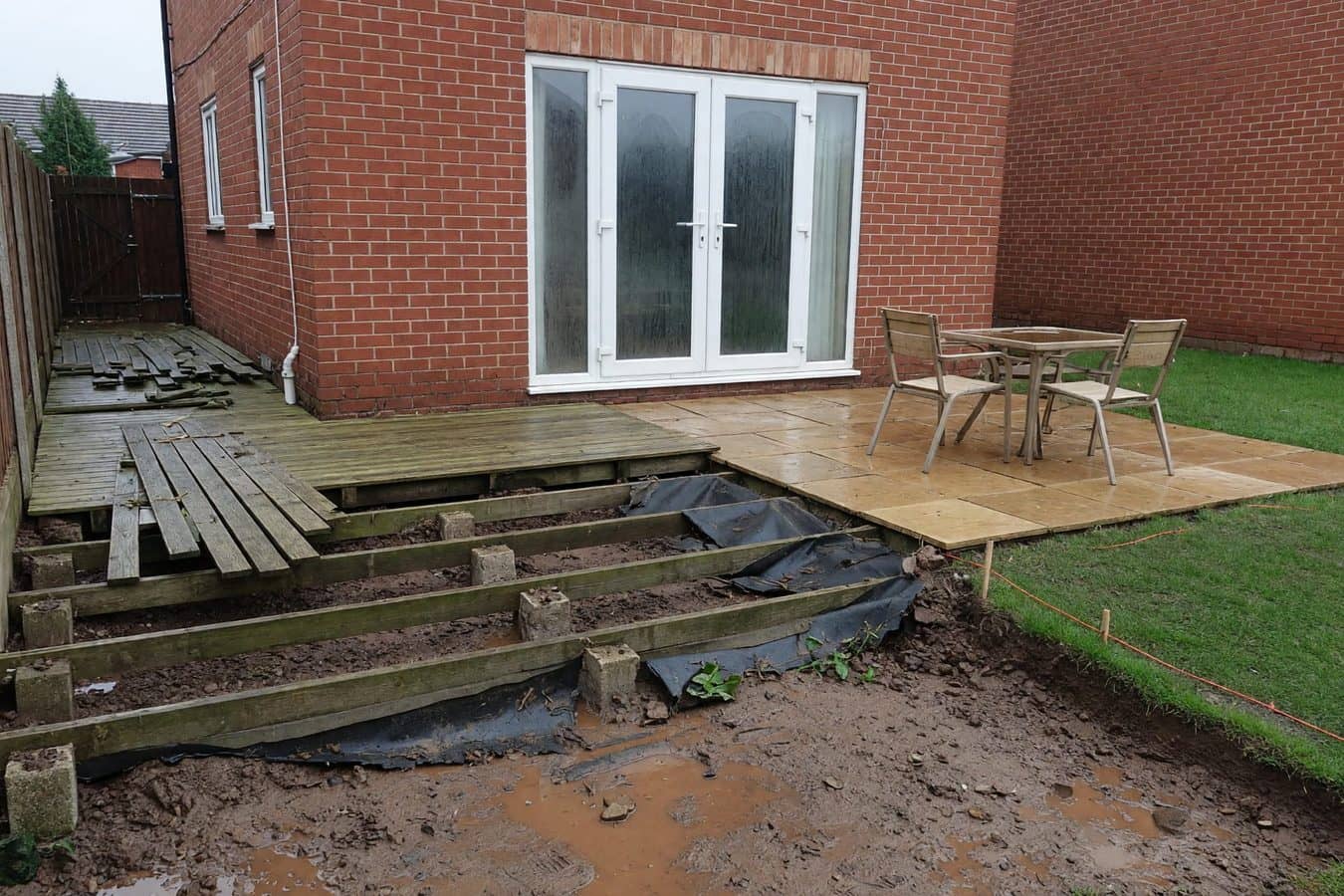 Timber decking stripped to joists and clay against a red-brick Lancashire semi