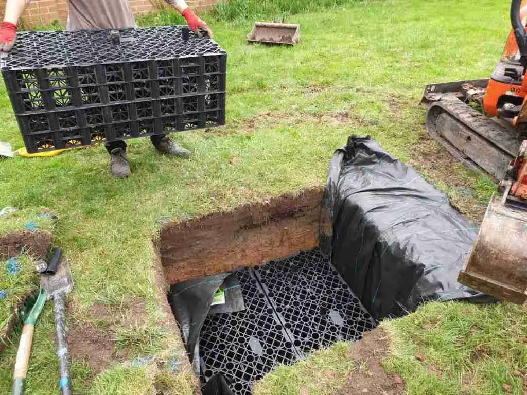 Square hole in garden filled with drainage cubes