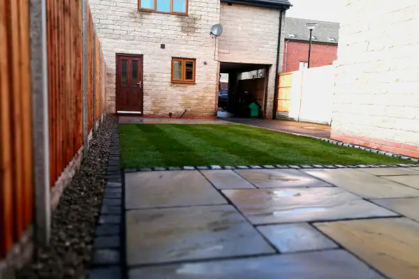 Low shot of newly landscaped garden Indian stone paving, block stone borders, turf, lap panel fencing, river gravel